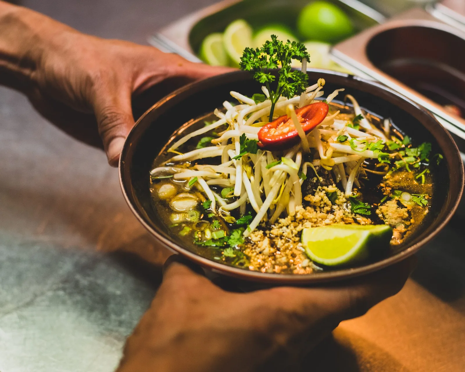Hands holding a vibrant gourmet noodle bowl by Graphic House Ireland.